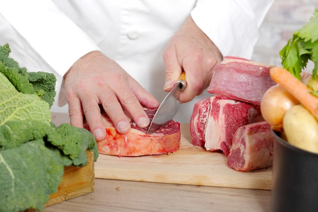 Chef couper la viande sur une planche de bois