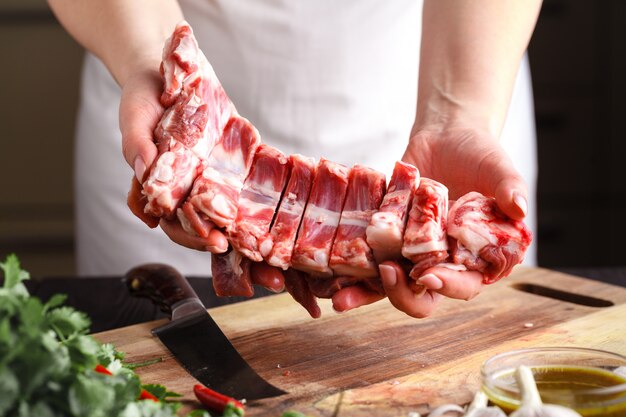 Chef avec un couteau à la main coupe de la viande fraîche sur une table