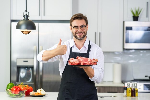 Chef cuisinant un filet de viande crue dans la cuisine concept de menu de restaurant portrait masculin du chef homme tenant m