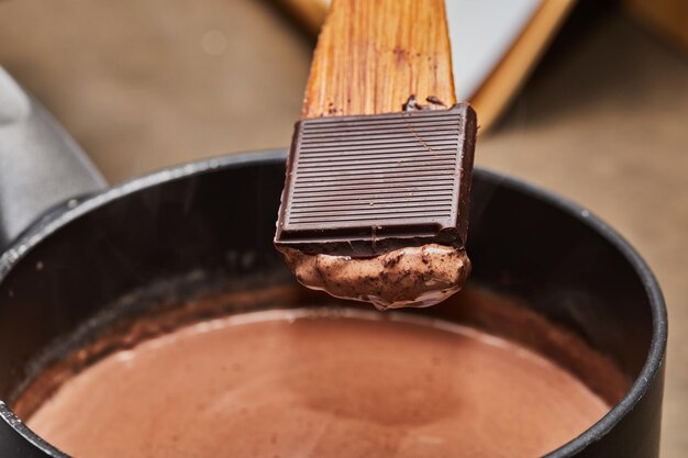 Chef cuisinant de la mousse au chocolat dans la cuisine à la maison avec une casserole et une cuillère