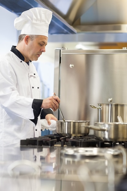 Chef de cuisine concentré en remuant dans le pot