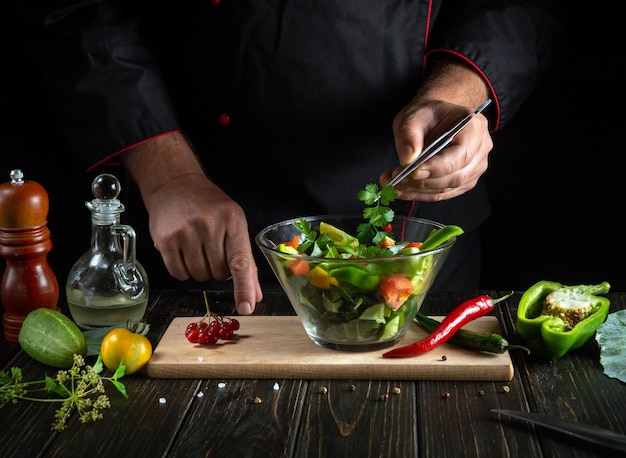 Le chef cuisine une délicieuse salade de légumes Nourriture végétarienne par les mains du cuisinier dans la cuisine