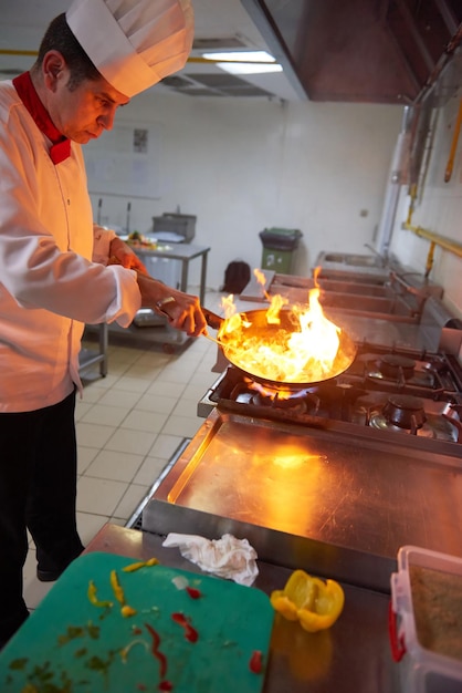 le chef de la cuisine de l'hôtel prépare des plats végétaux avec le feu