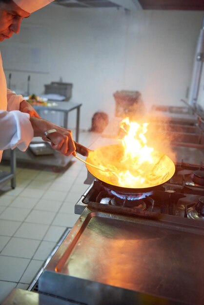 le chef de la cuisine de l'hôtel prépare des plats végétaux avec le feu