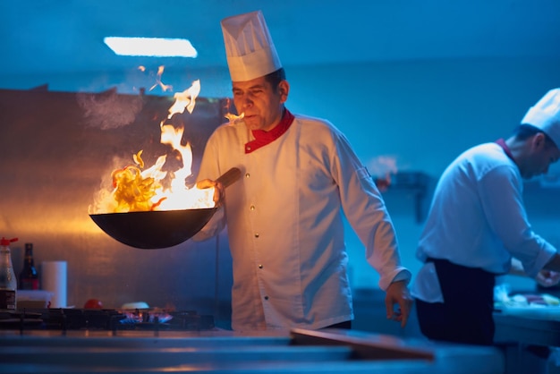 le chef de la cuisine de l'hôtel prépare des plats végétaux avec le feu