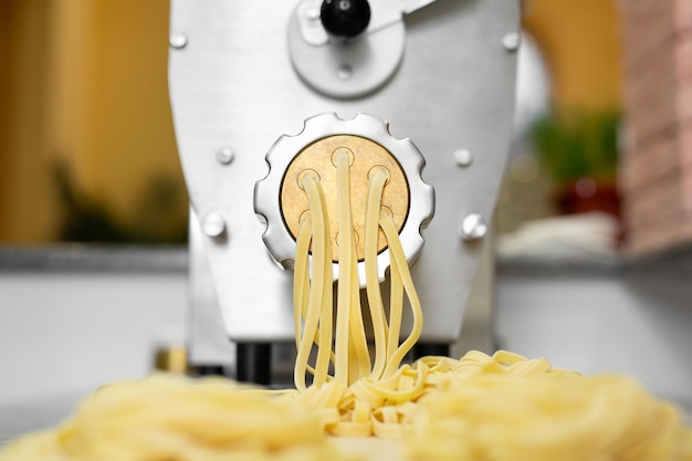 Le chef cuisine des spaghettis italiens à l'aide d'une machine à pâtes Tirant des pâtes longues dans la cuisine du restaurant