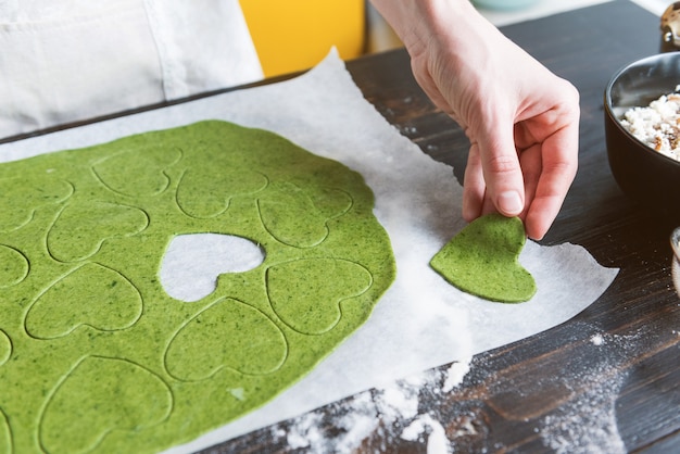 Le chef cuisinier prépare pas à pas des raviolis verts en forme de cœur pour un dîner de fête