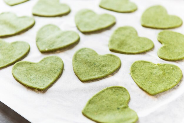 Le chef cuisinier prépare pas à pas des raviolis verts en forme de cœur pour un dîner de fête