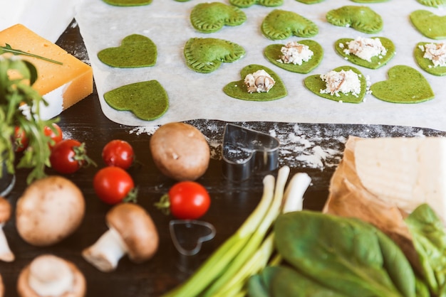 Le chef cuisinier prépare pas à pas des raviolis verts en forme de cœur pour un dîner de fête