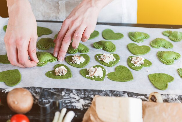 Le chef cuisinier prépare pas à pas des raviolis verts en forme de cœur pour un dîner de fête