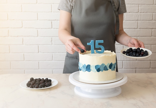 Le chef décore le gâteau avec des myrtilles et des mûres. gâteau pour 15 ans