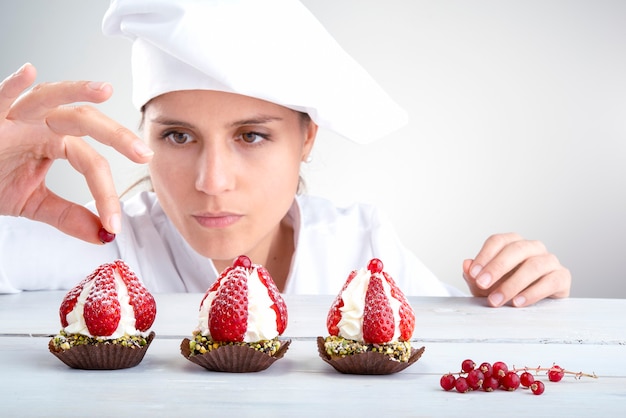 Photo le chef décore de petits cupcakes aux fraises