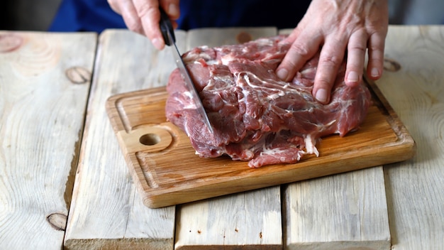 Le chef découpe la viande crue sur le plateau.