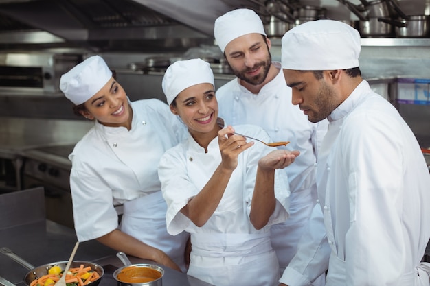 Chef dégustation de nourriture à un collègue dans la cuisine