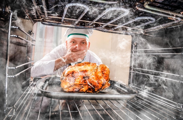 Photo le chef drôle a négligé le poulet rôti dans le four, elle avait donc brûlé, vue de l'intérieur du four. cook perplexe et en colère. le perdant est le destin !