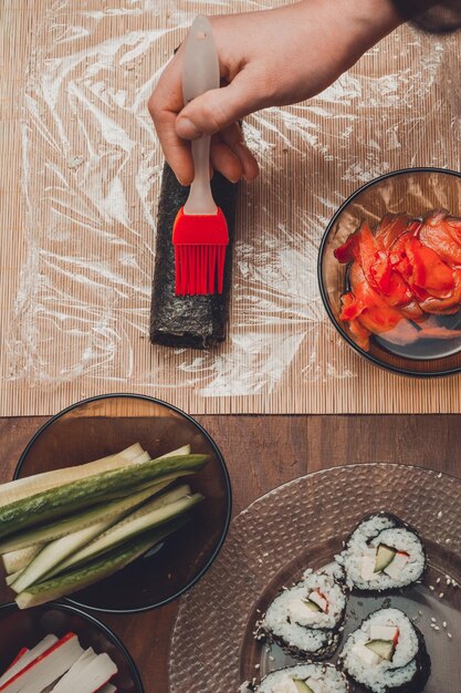 Le chef du restaurant oint le pinceau de la sauce sur le rôle des sushis