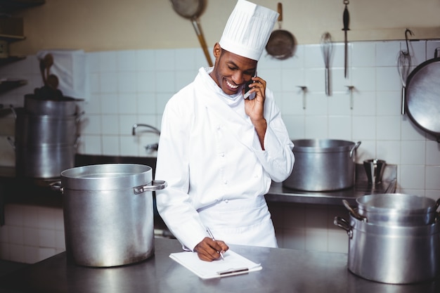 Chef écrit sur presse-papiers tout en parlant au téléphone