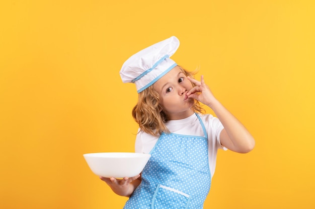 Chef enfant drôle cuisinier avec portrait de studio de plaque de cuisine Chef enfant garçon sous forme de cuisinier Enfant garçon avec tablier et toque préparant un repas sain sur fond isolé de studio Processus de cuisson