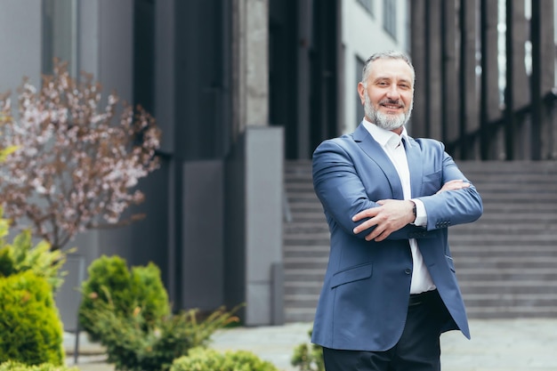 Chef d'entreprise patron réussi homme regardant la caméra avec les bras croisés et homme d'affaires aux cheveux gris souriant en costume d'affaires