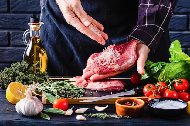 Le chef est en train de sauter du sel sur les steaks.