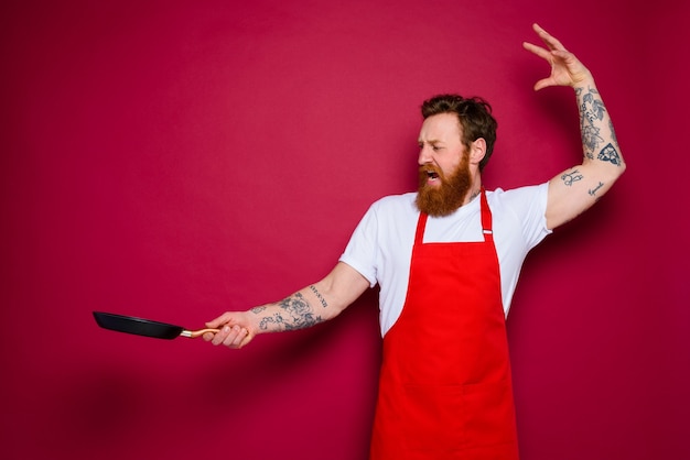 Le Chef Fâché Avec La Barbe Et Le Tablier Rouge Cuisine Avec La Casserole