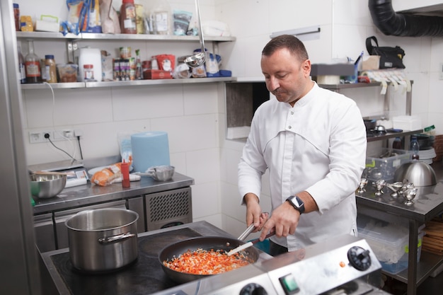 Chef faisant frire un mélange de légumes sur la poêle, travaillant au restaurant, espace de copie