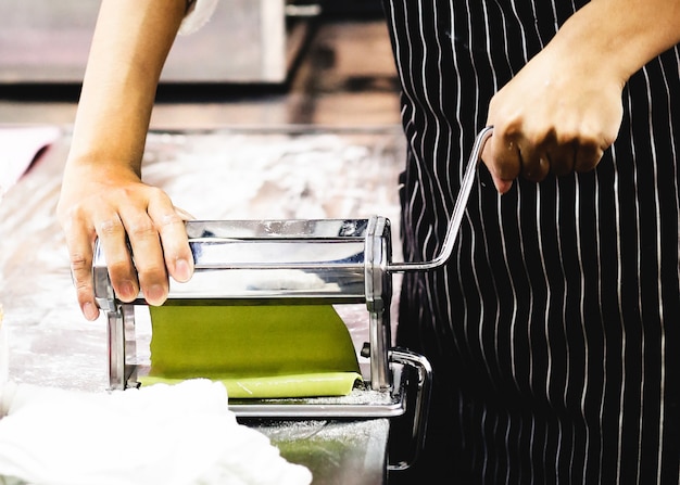 Chef faisant la pâte pour la pâtisserie, pâtes fraîches et machine à pâtes dans la cuisine