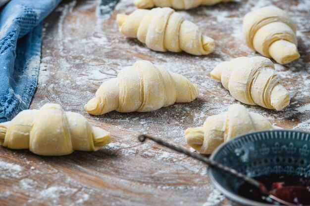 Le chef fait manuellement des croissants sur la table avec des ingrédients.