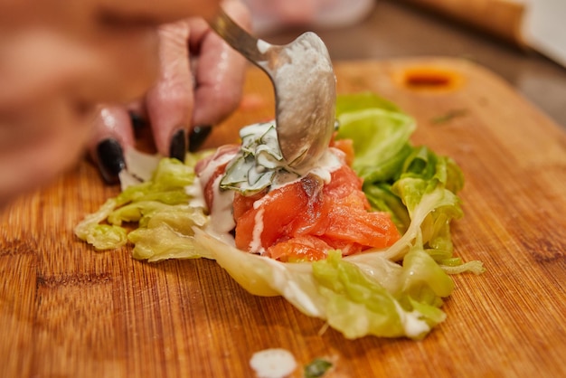 Le chef fait des rouleaux de chou avec des carottes de saumon et de la sauce dans la recette française de la cuisine