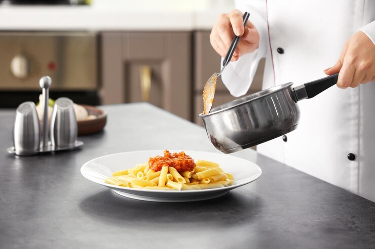 Photo chef féminin ajoutant de la sauce bolognaise à de délicieuses pâtes sur assiette