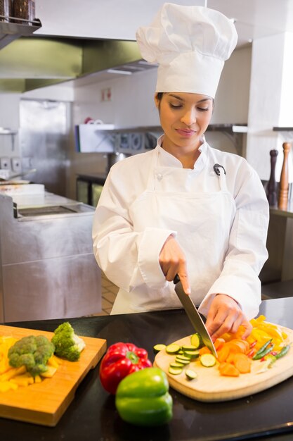 Chef féminin coupe légumes dans la cuisine