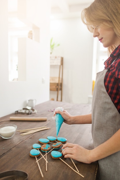 Photo chef féminin cuisson gâteau bleu de pâques apparaît sur table rustique en bois dans la cuisine