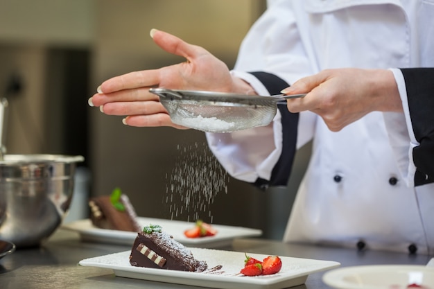 Chef féminin finissant une assiette à dessert