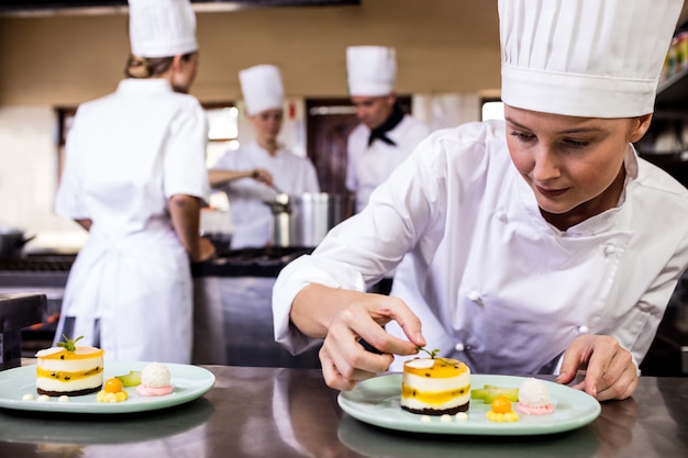 Chef féminin garnir de délicieux desserts dans une assiette