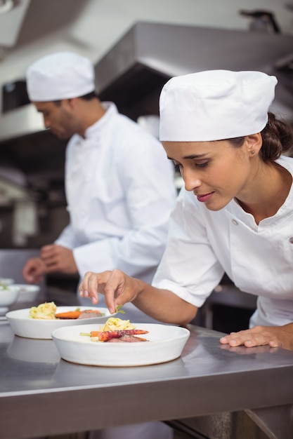 Chef féminin garnir la nourriture dans la cuisine