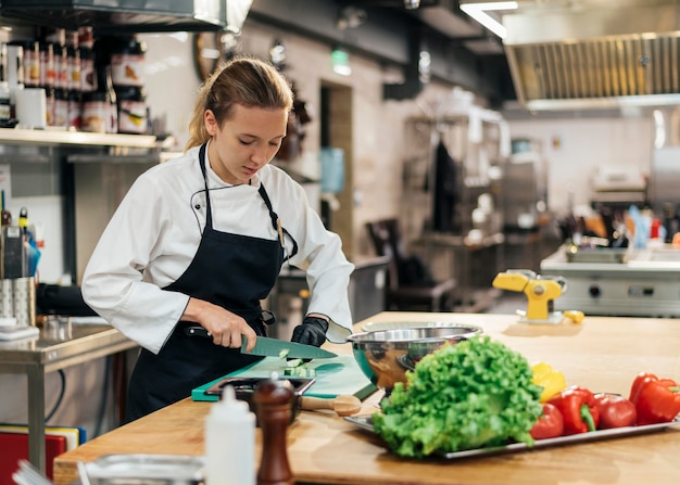 Chef féminin avec tablier de coupe de légumes