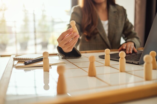 Chef de femme d'affaires choisissant des personnes en bois d'un groupe d'employés sur un tableau de planification