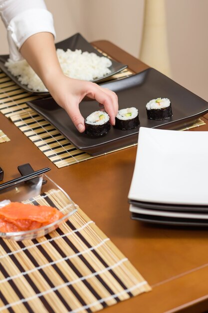 Chef de femme plaçant des rouleaux de sushi japonais sur un plateau