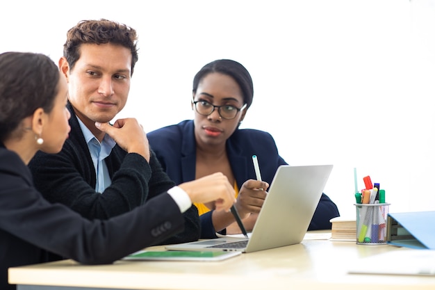 Chef de file d'un homme d'affaires lors d'une réunion avec deux femmes analysant des documents sur un ordinateur portable au bureau à domicile.