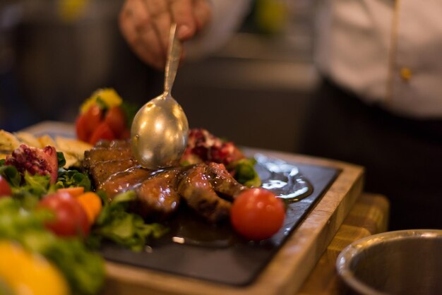 Chef finissant une assiette de viande de steak avec une vinaigrette enfin et presque prête à servir à table