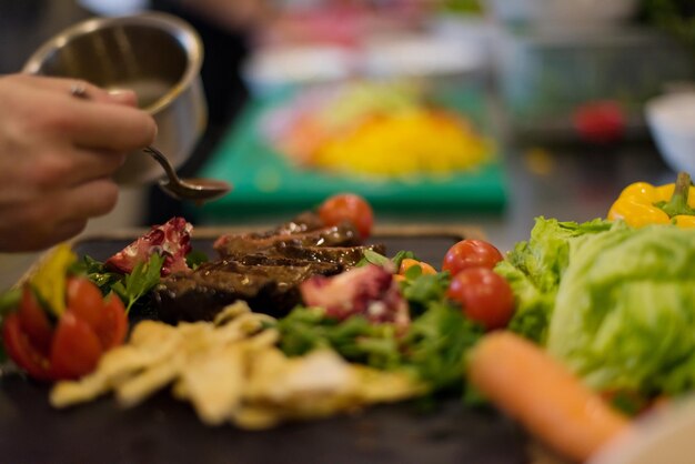 Chef finissant une assiette de viande de steak avec une vinaigrette enfin et presque prête à servir à table