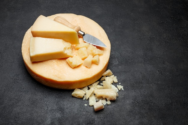 Chef de fromage à pâte dure parmesan et morceaux sur table en béton