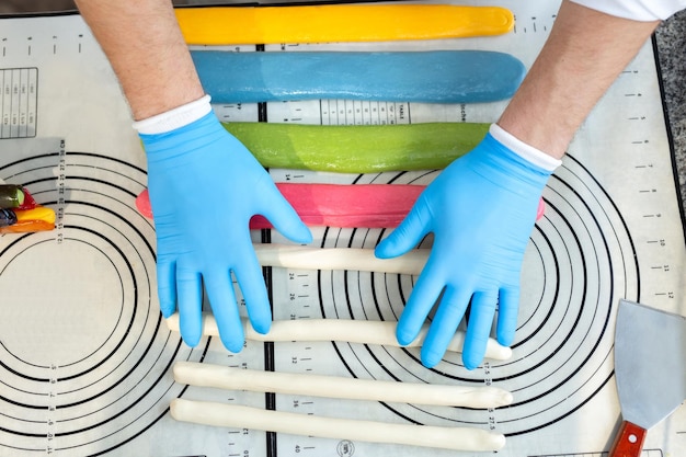 Le chef en gants colle des sucettes au caramel chaud multicolores sur un bâton Travail fait à la main