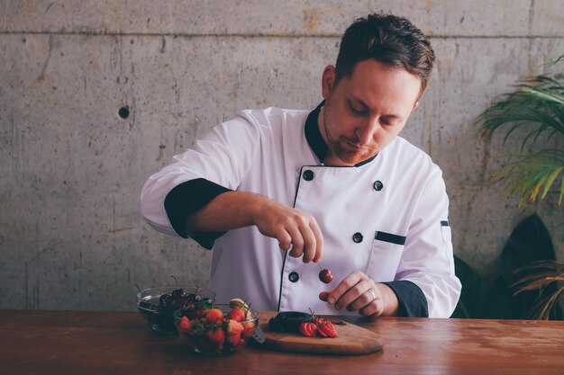 Chef homme mettre cerise à la décoration de gâteau