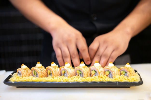 Chef japonais faisant des sushis au restaurant. Cuisine japonaise traditionnelle, rouleau de sushi au saumon.