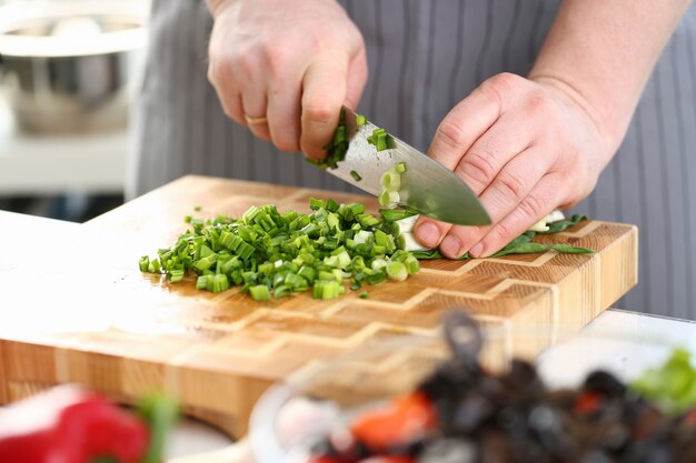 Chef mains tenant un couteau, couper l'oignon vert