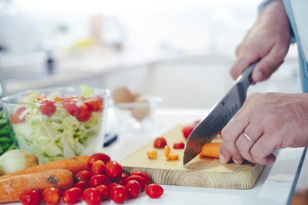 Chef à la maison à l'aide d'un couteau coupant des légumes crus frais Cuisinière à la maison faisant un repas de légumes sains coupant des légumes nourriture et boisson images 4k Un homme préparant des salades dans la cuisine