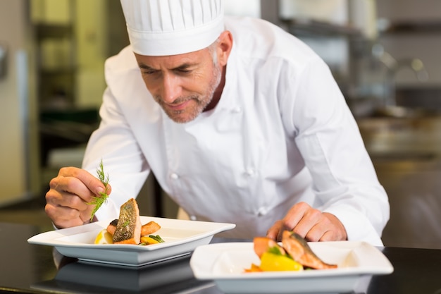 Chef masculin concentré garnissant la nourriture dans la cuisine