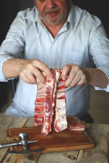 Un chef masculin coupe des côtes de porc crues