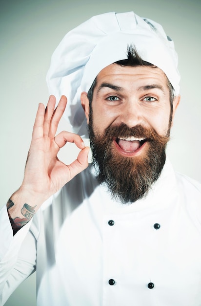 Chef masculin professionnel en uniforme blanc faisant un geste correct souriant cuisinier barbu montrant signe ok